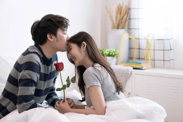 Valentine's Day, Asian couple is spending time together in home, He gave her flowers and kissed her warmly and tenderly.