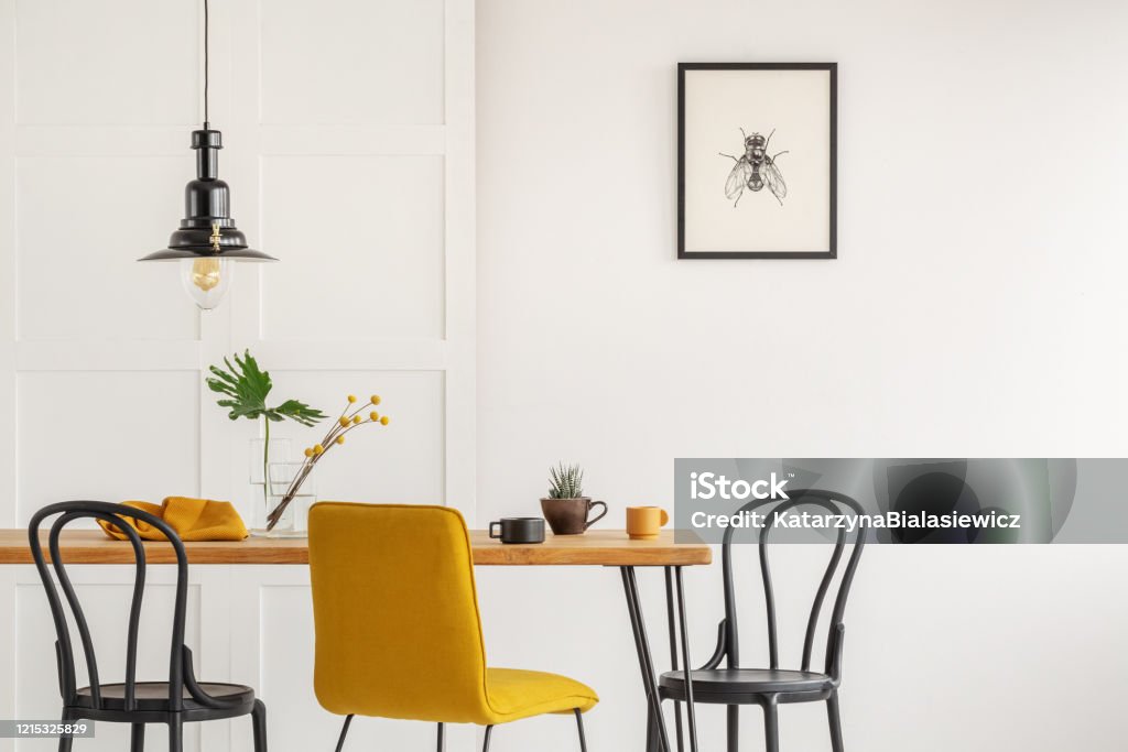 Stylish yellow chair at wooden dining table in trendy interior Kitchen Stock Photo