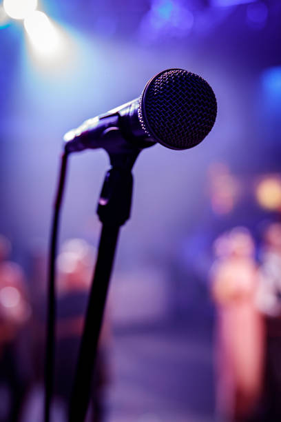 istock Microphone head on stage in a dark room. 1215328604