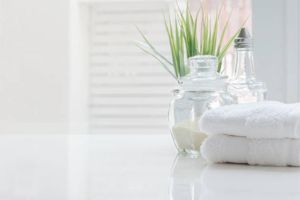 istock White folded towels and glass bottle on white table with copy space on blurre bathroom background. 1215329553