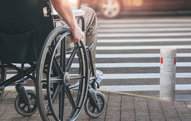 Disablee man on wheelchair crossing the road. Disabled man on wheelchair preparing to cross the road on pedestrian crossing, copy space. zebra crossing photos stock pictures, royalty-free photos & images