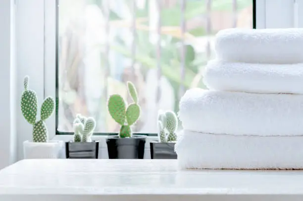 Photo of Clean towel on white table near window sill.