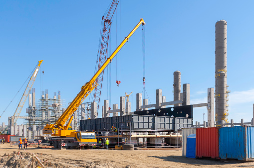 Yellow hydraulic lifting platform with bucket cabin on a telescopic lift near the building structure.