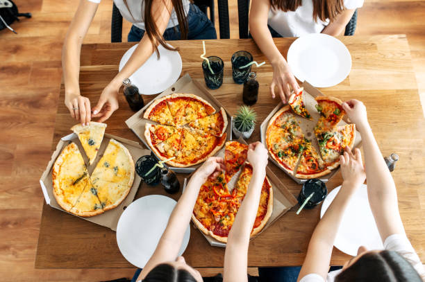 istock Appetizing pizza on the table and hands above it 1215334981