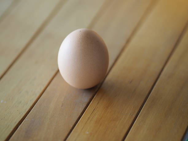 istock Fresh egg on brown wooden desk 1215335128
