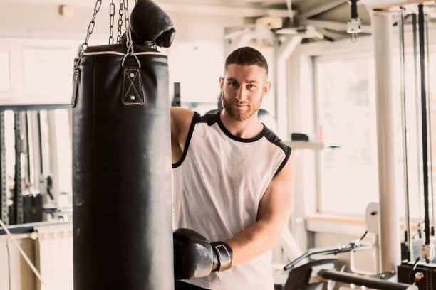 istock Young boxer during training with punching bag posing looking at camera 1215339148