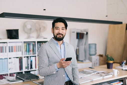 Portrait of happy and proud Asian man at his offfice