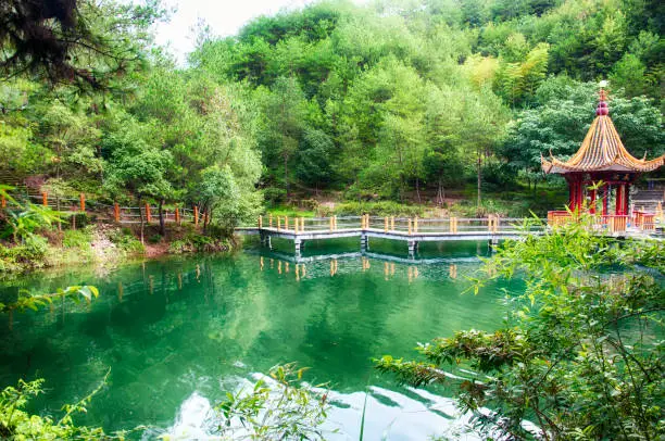 A green lake and chinese gazebo at the feng huang shan gong yuan or phoenix mountain park in Lishui China on an overcast day in Zhejiang province.