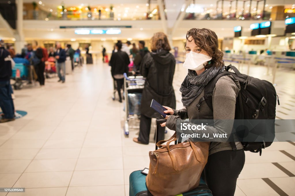 At the airport with a face mask Woman waiting in a long line for a flight wearing a N95 face mask during a global pandemic Airport Stock Photo