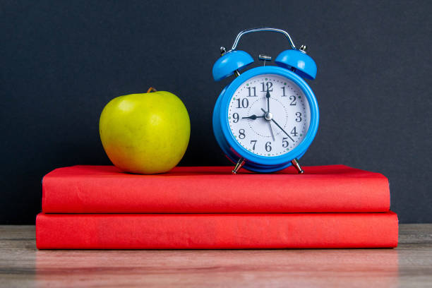 Blue watch and green apple stand on red books