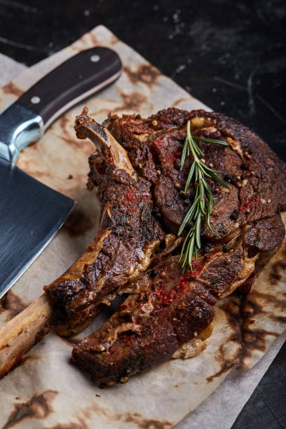 istock Tomahawk steak with vegetables and a knife on the table. Grilled meat with grilled vegetables and fresh vegetables on the table 1215343071