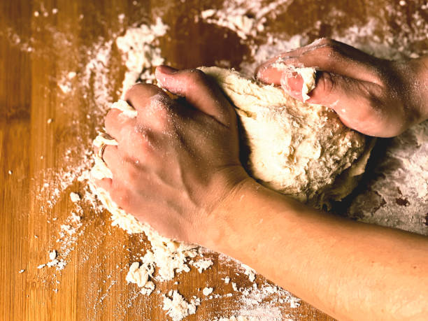 istock female hand kneading a flour dough by rolling it on a wooden board 1215343378