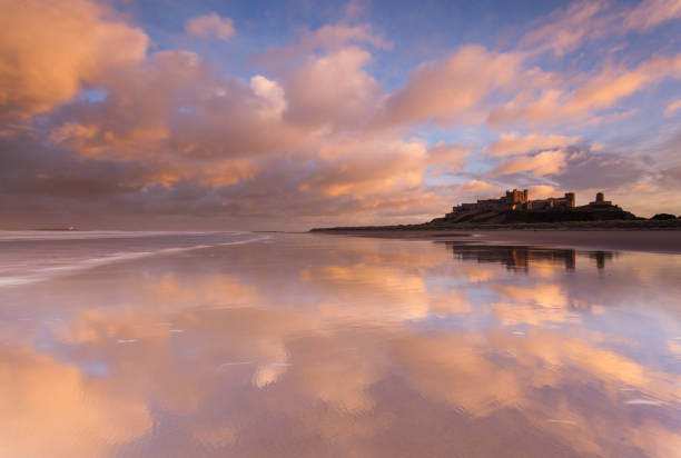 castillo y playa de bamburgh, northumberland - bamburgh northumberland england beach cloud fotografías e imágenes de stock