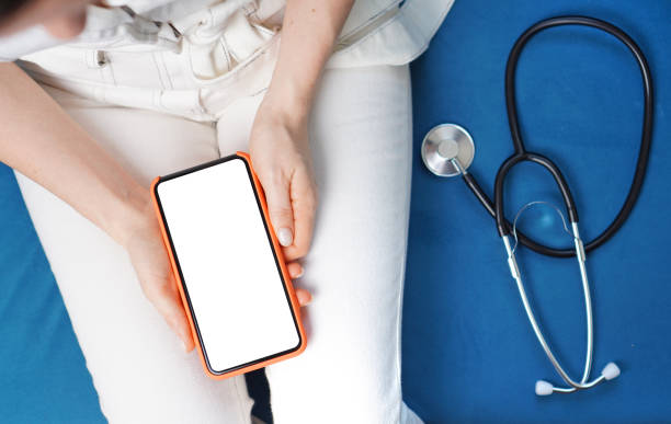 istock Online medical assistant background. Doctor holding smartphone with empty screen. Remote medical control concept. 1215346358