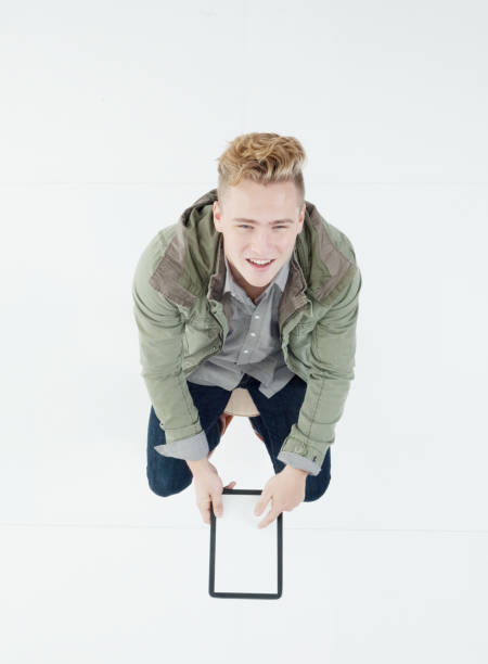 istock Caucasian male sitting in front of white background wearing jacket and using touch screen 1215348948
