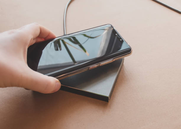 istock Woman's hand brings phone to wireless charger 1215349086