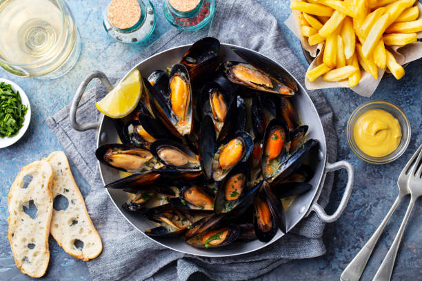 Mussels with french fries and white wine in cooking pan. Grey background. Close up. Top view. stock photo