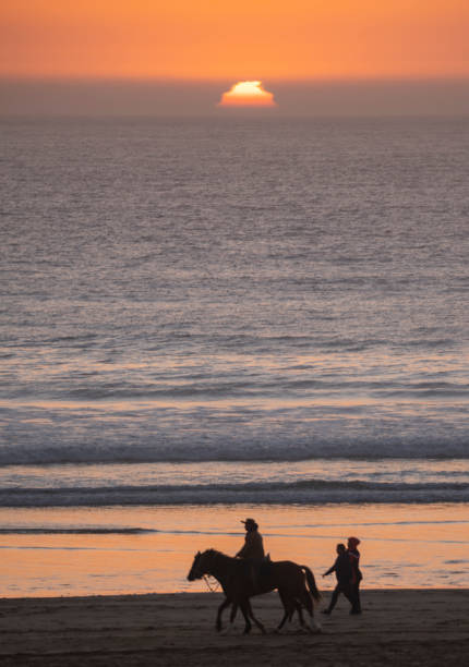 Sun setting over calm sea with gentle waves and rocky shore