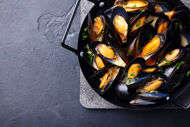 istock Mussels with herbs and sauce in black pan. Copy space. Top view. 1215360519