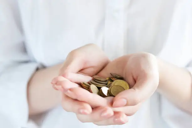 Photo of Handful of coins in palm hands isolated on white