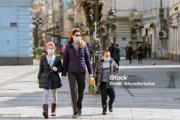 Madre Y Dos Niños Pequeños Caminando Por Las Calles De La Ciudad Usando Máscaras Faciales Contra Coronavirus Covid 19 Pandemia Vista De La Calle En El Centro De La Ciudad Foto de stock y más banco de imágenes de Máscara protectora