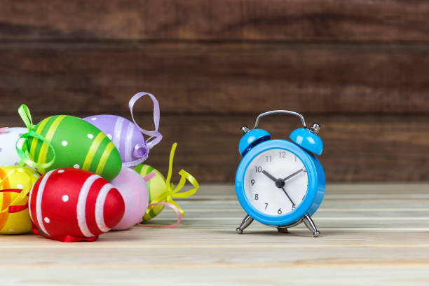 Easter eggs and alarm clock on a wooden table