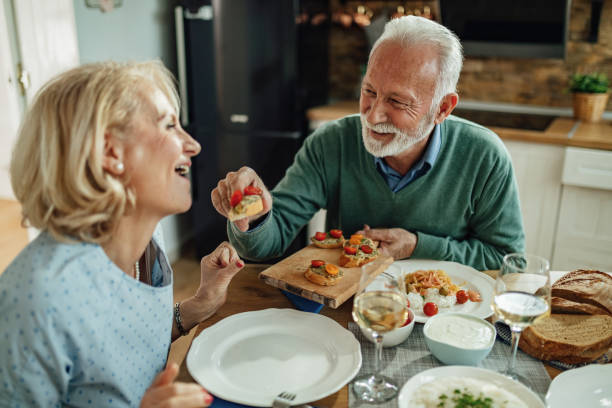 istock Happy mature man feeding his wife at dining table. 1215369485