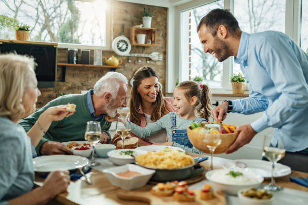 Happy extended family having fun during family lunch in dining room. Happy multi-generation family gathering around dining table and having fun during a lunch. meal stock pictures, royalty-free photos & images