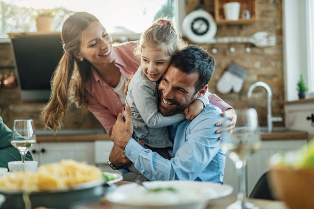 giovane famiglia amorevole che si abbraccia nella sala da pranzo. - dinning table foto e immagini stock