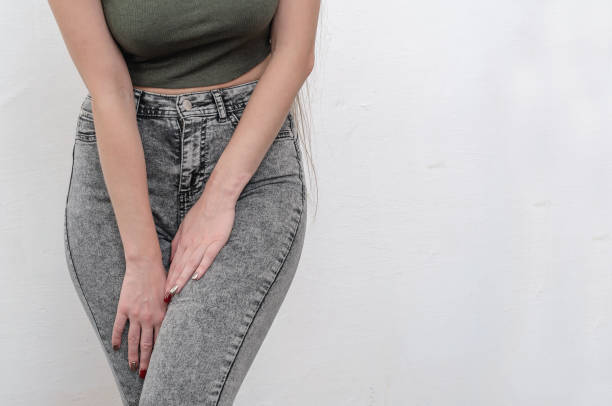 istock Young slim girl in jeans holds hands pressed between her legs. 1215371813