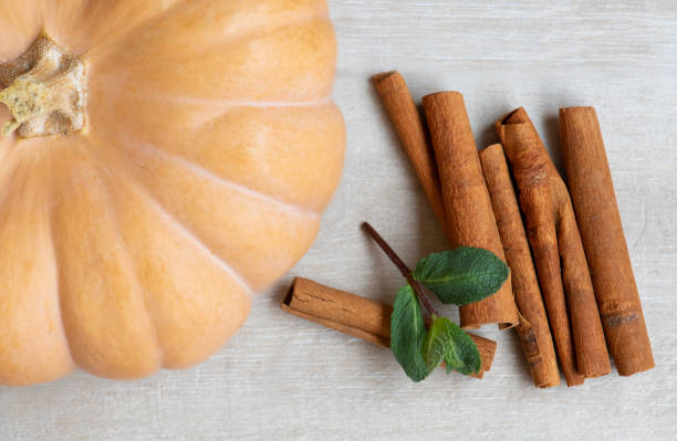 istock Top view.  Orange pumpkin, cinnamon sticks on the wooden background. 1215373683