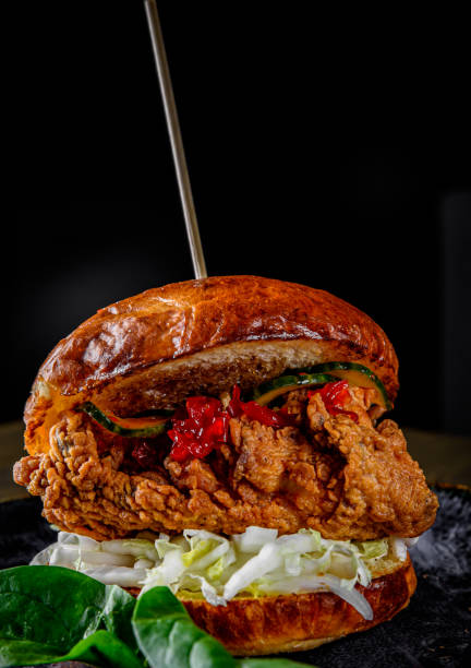 istock Close up on crispy chicken burger with vegetables on dark background 1215373956