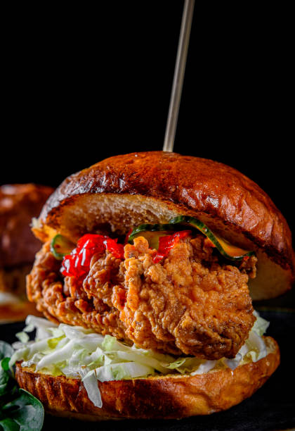 istock Close up on crispy chicken burger with vegetables on dark background 1215374074