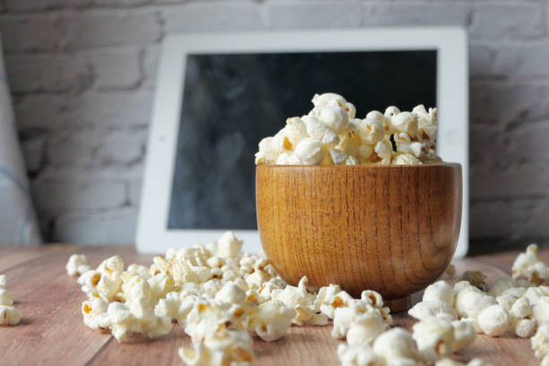 Close up of popcorn in a bowl with digital tablet on table .
