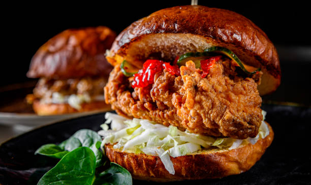 istock Close up on crispy chicken burger with vegetables on dark background 1215374351