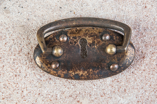 Metal ornaments and hinges on two brown wooden church doors.