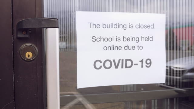 Sebuah pintu ke sekolah dengan tanda yang menyatakan bahwa itu ditutup oleh pandemi Virus Corona COVID-19.