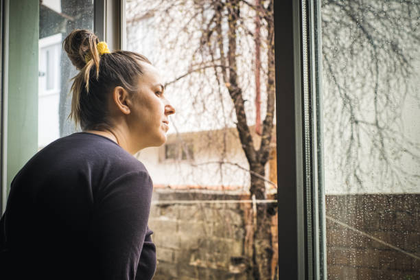istock adult woman looking through the window 1215379732
