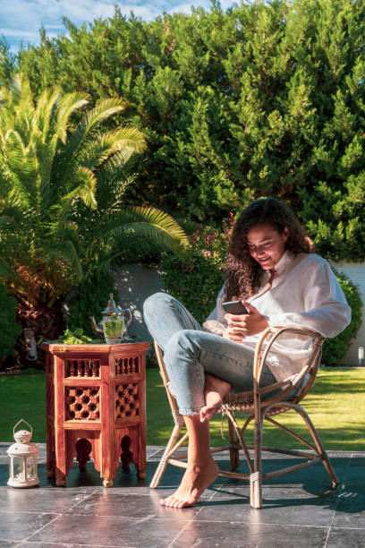 istock Ethnic woman isolated on the backyard using technology at home. 1215379856