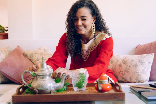 Moroccan female preparing traditional arab tea at home. Arabian culture and traditions. Muslim lifestyle at home. Arabian young woman with ethnic features smelling a branch of fresh green mint. moroccan woman stock pictures, royalty-free photos & images