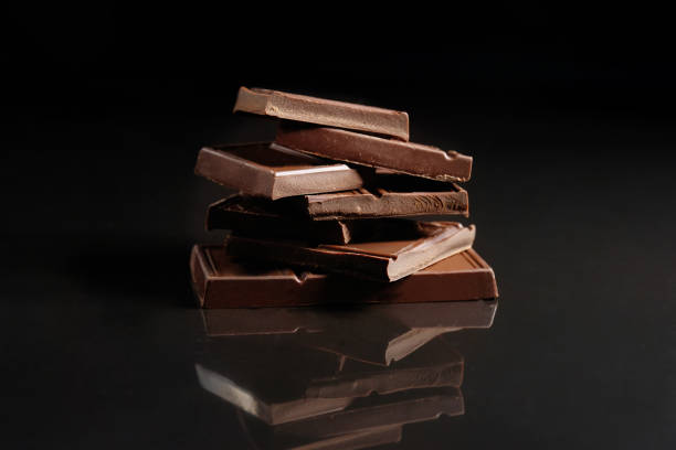 istock Milk chocolate with reflection on a black background. 1215380998