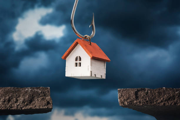 A toy house on a hook hanging over a precipice. Debt concept stock photo