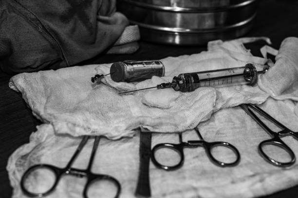 Retro syringe, and medical surgical instrument on a wooden table. Vintage style. Surgical instruments covered with gauze. Lying on the table in the operating room operating room photos stock pictures, royalty-free photos & images