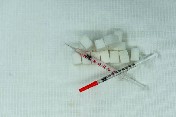 spritzen für insulin auf dem hintergrund von zuckerwürfeln. diabetes-impfstoff - syringe vaccination vial insulin stock-fotos und bilder
