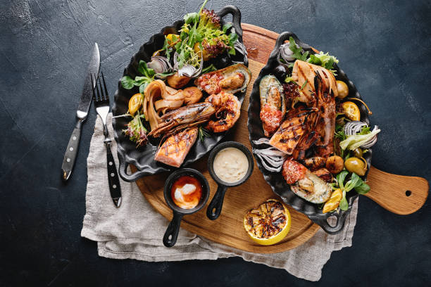 istock Assorted seafood on plates. Beautiful composition on a served seafood table, squid, shrimp, salmon steak and octopus. Food photo, low key, traditional Italian cuisine. Top view, save the space 1215385055