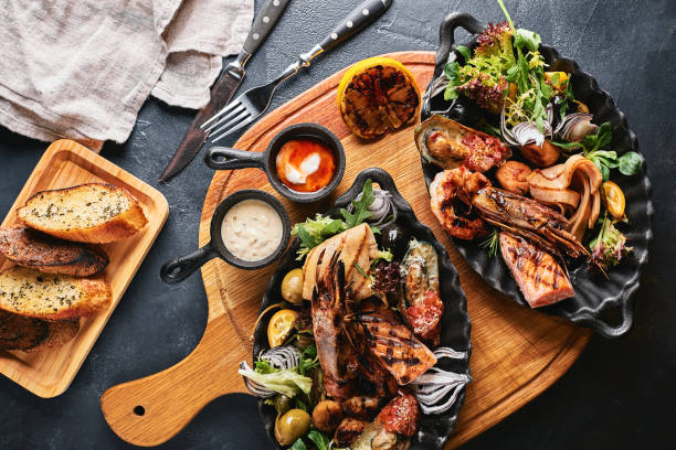 istock Assorted seafood on plates. Beautiful composition on a served seafood table, squid, shrimp, salmon steak and octopus. Food photo, low key, traditional Italian cuisine. Top view, save the space 1215385068