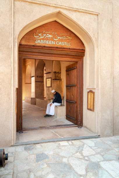 バハラのジャブリーン城の入り口にあるオマーンの男、オマーンのスルタン - bahla fort ストックフォトと画像
