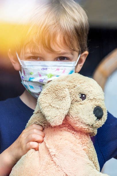 mały chłopiec patrząc przez okno za pomocą maski chirurgicznej - children only healthy lifestyle vertical close up zdjęcia i obrazy z banku zdjęć