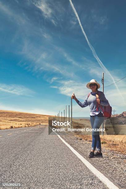 Beautiful Woman Hitchhiking On Road In Forest Hitchhiking With Thumbs Up In A Countryside Road Travelling And Hitchhiking Concept Stock Photo - Download Image Now