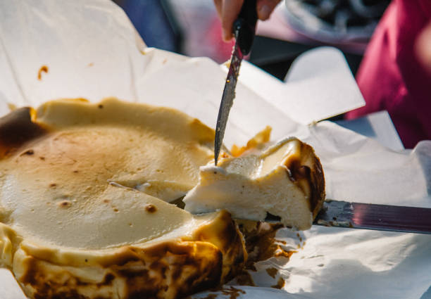 Close up female hand taking a slice of homemade Traditional La Vina Basque burnt cheese cake with spatula on table